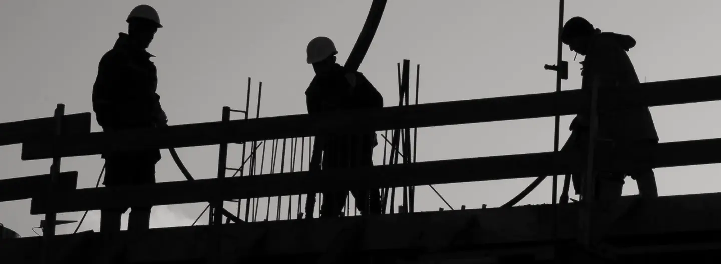 Image of silhouetted men working on a construction site.